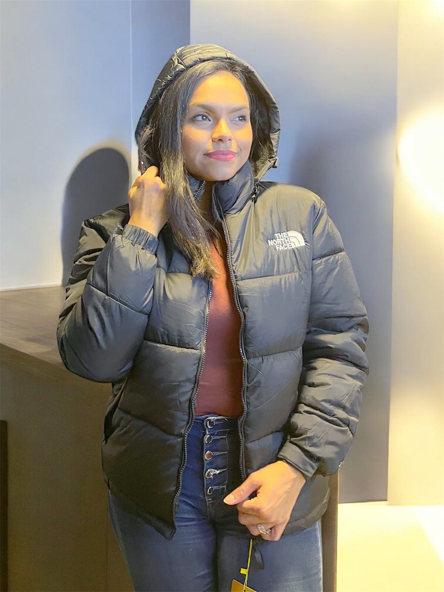 Mujer mostrando interior de chaqueta acolchada negra con polar térmico, ideal para invierno y bajas temperaturas.