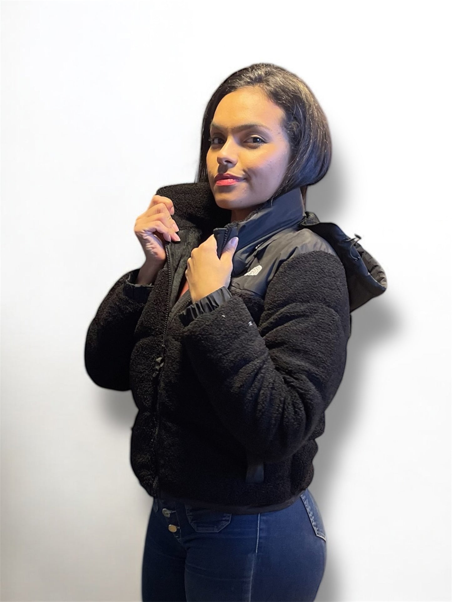 Vista lateral de chaqueta teddy negra con gorro, diseño moderno y ajustado para climas fríos.