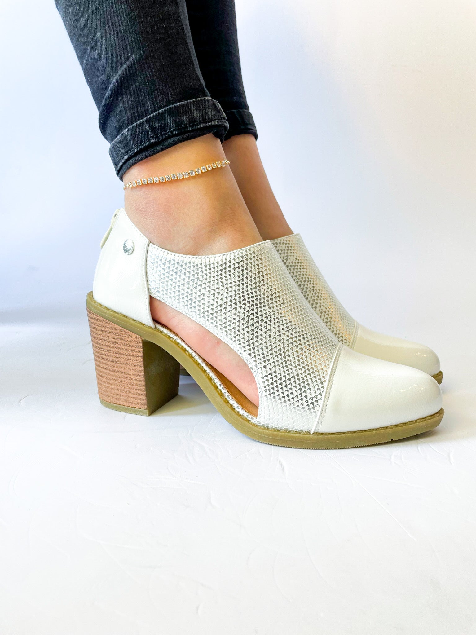 Botín Serena color blanco en ecocuero con taco cuadrado de 6 cm, detalle lateral calado y terraplén de goma especial para mayor comodidad.