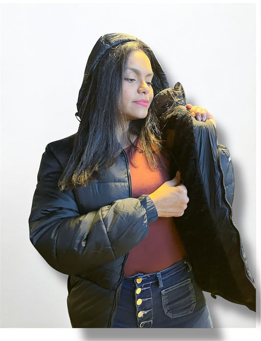Mujer posando con chaqueta negra de invierno, con capucha y diseño moderno, fondo blanco.